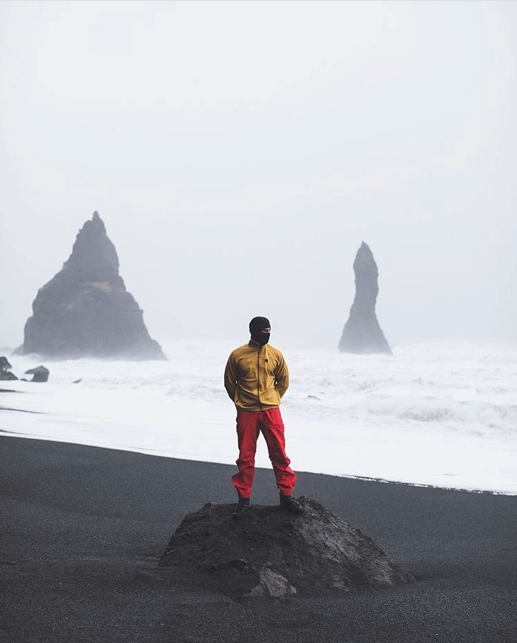 Mads Emil Møller stands on a rock at a misty beach with sea stacks in the background.