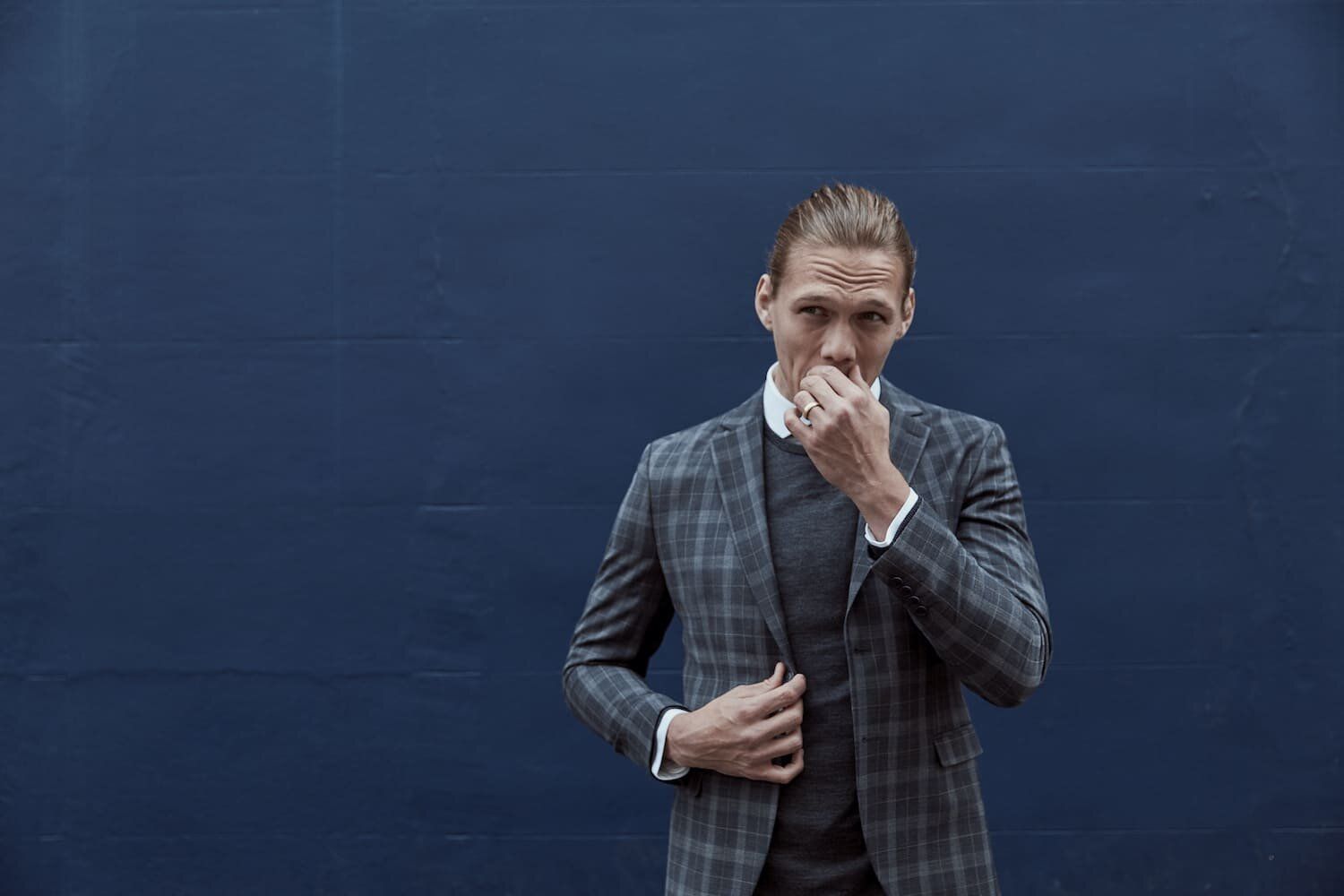 Jannik Vestergaard poses in a stylish suit against a dark blue background.
