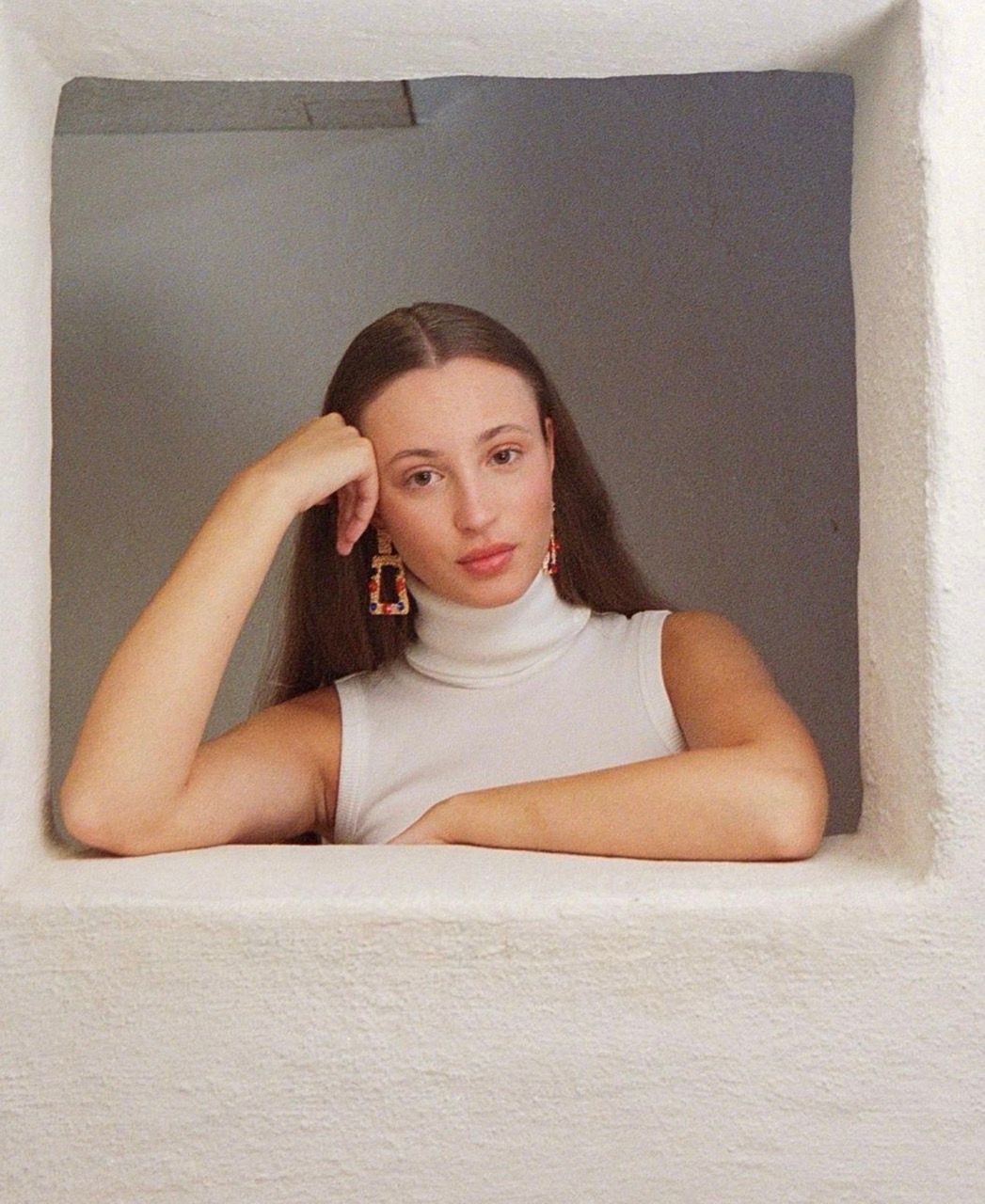 Josephine Højbjerg poses thoughtfully in a white turtleneck, framed by a textured wall.