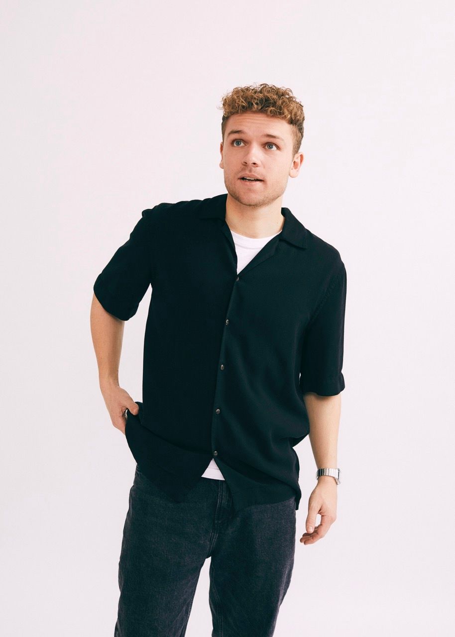 Rasmus Brohave stands in a casual pose against a light background, looking engaged.