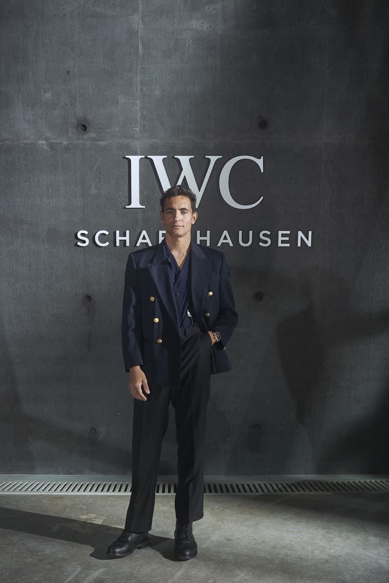 Jonathan Harboe stands confidently in front of an IWC Schaffhausen backdrop.
