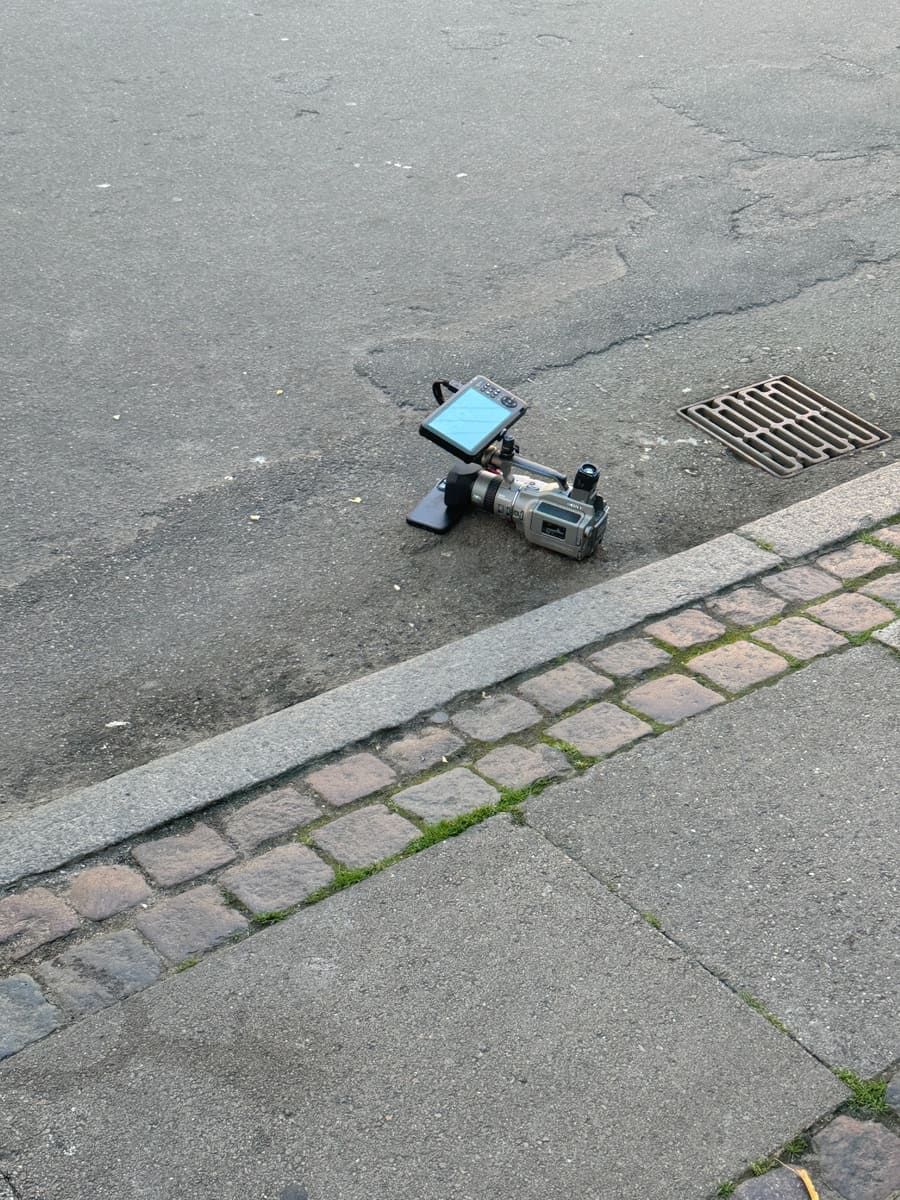 A video camera and monitor placed on a cobblestone street beside a drainage grate.