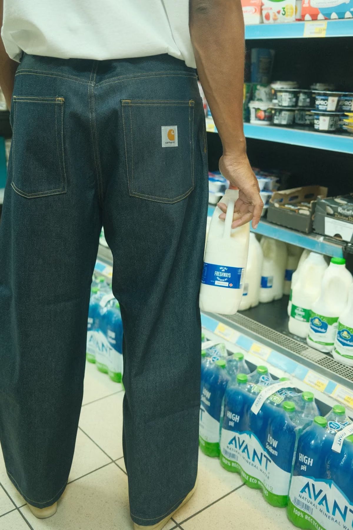 Mathias Zanka stands in a grocery aisle holding a bottle of milk.