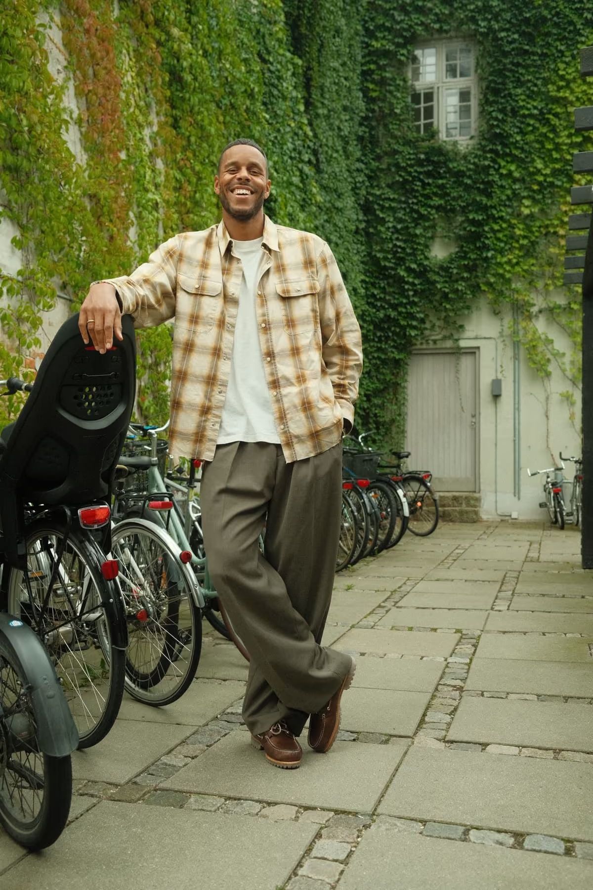 Mathias Zanka stands casually among bicycles in a green, ivy-covered courtyard.